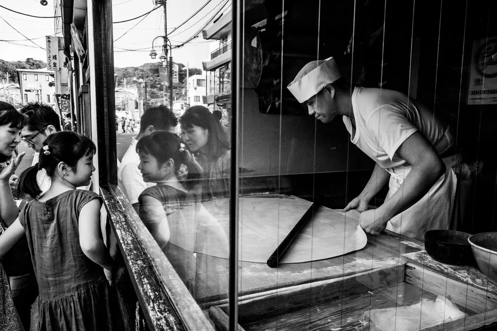 Children watching a baker shape dough through a shop window. Photograph by Maulik Shah