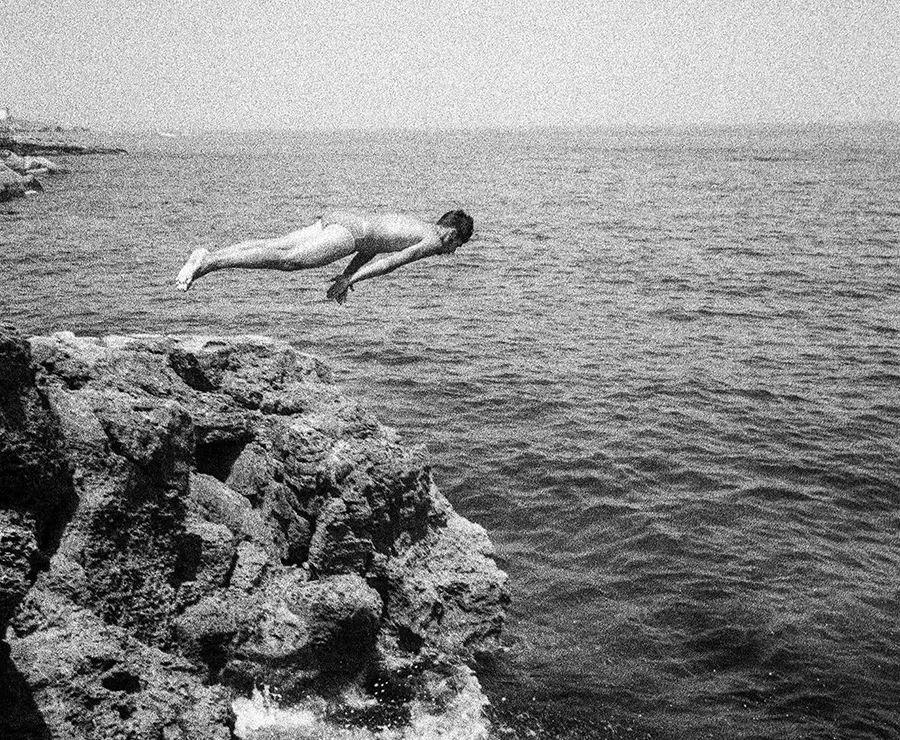 A man diving from a rocky outcrop into the sea. Photograph by Isaac Gens